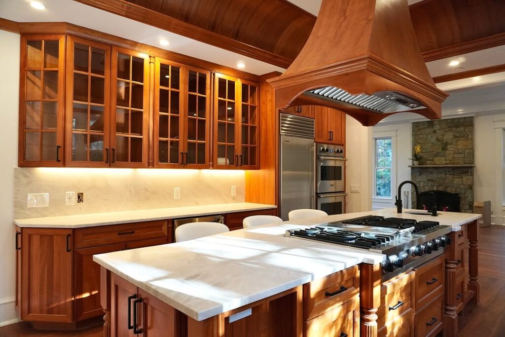A Red Oak Kitchen Featuring a Marble Island and Glass Front Cabinets