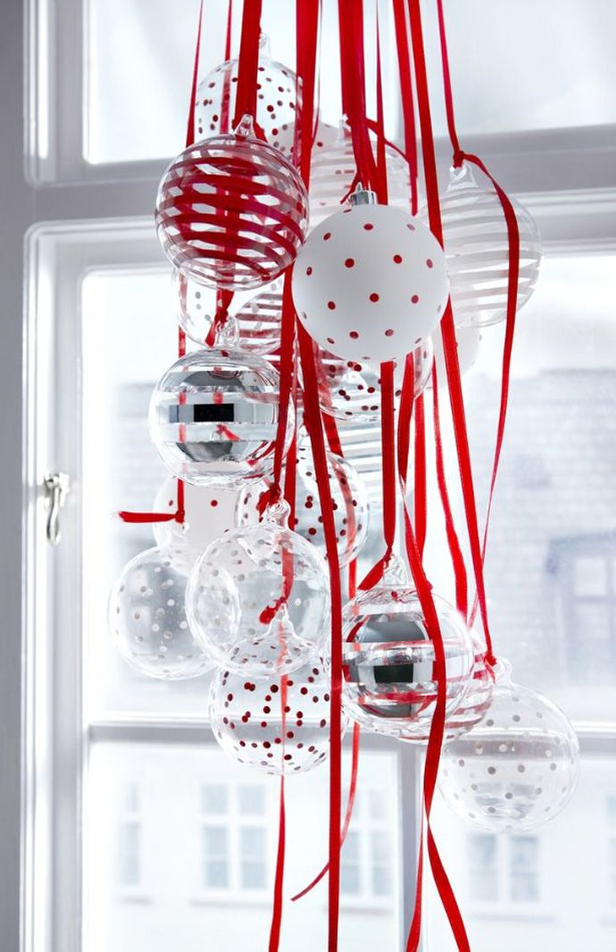 Beautiful glass ornaments in red polka dots and stripes hung by window.