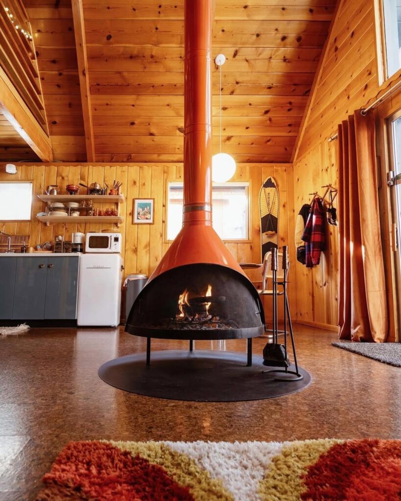 Cabin-Inspired Interior with an Orange Cone Fireplace in Retro Style
