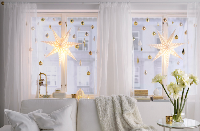 Large bright star lights hung with smaller ornaments as Christmas window decorations.