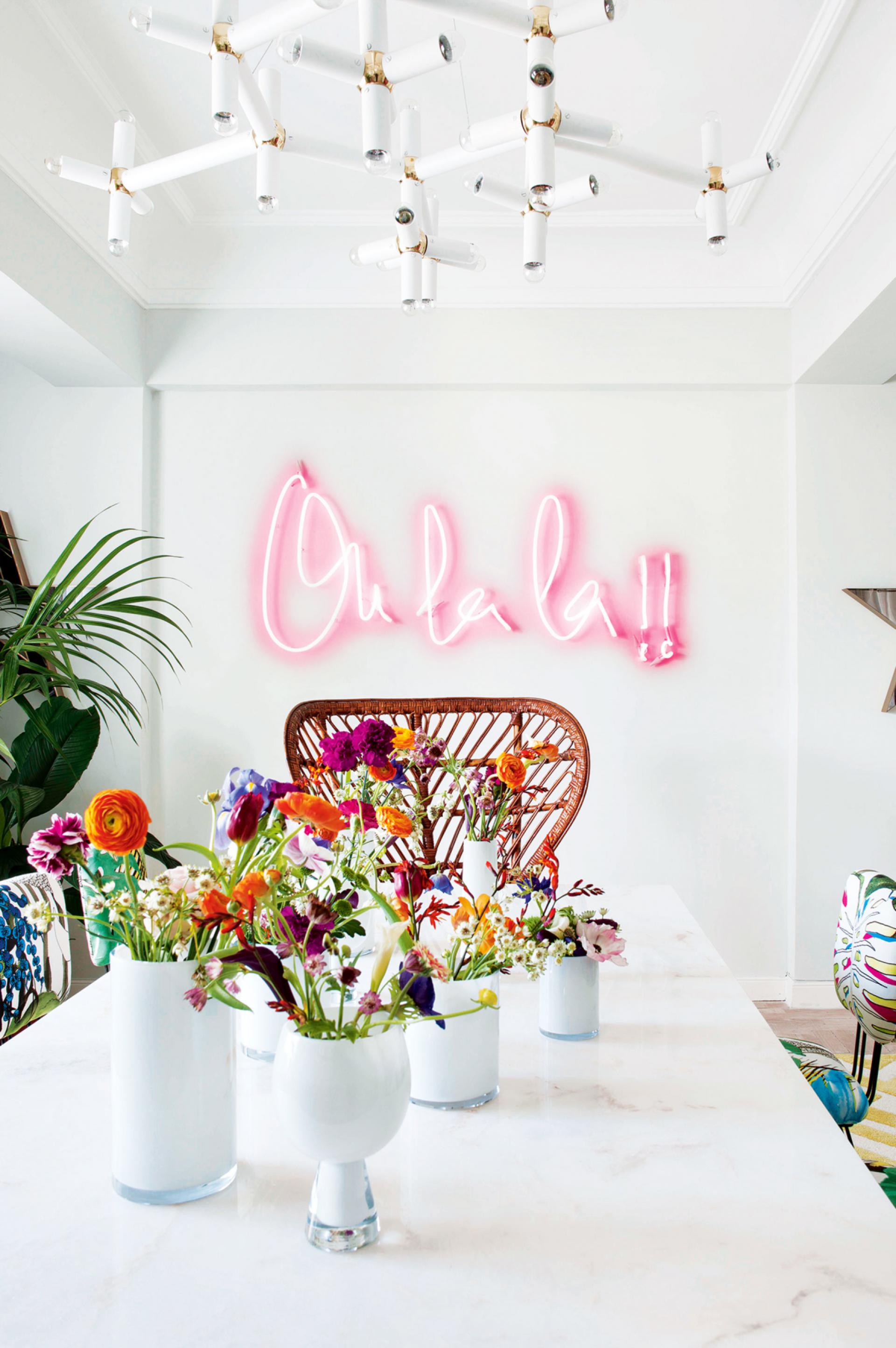 A magenta neon sign breaking up a white dining room