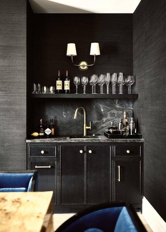 Contemporary black wet bar features a Vendome double sconce on blackcloth wallpaper over a black marble leathered countertop with polished brass gooseneck faucet.