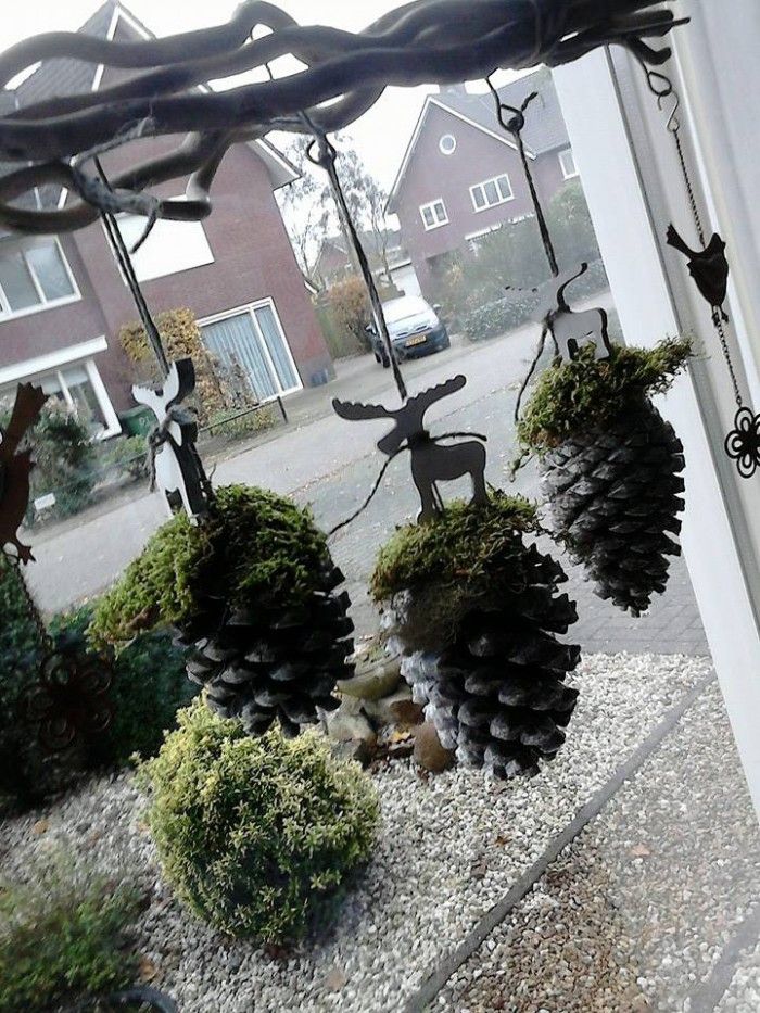 Pinecones with moss and reindeer figurines hung in window as decorations.