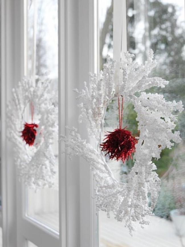 Wintery white and red wreaths hung in window.