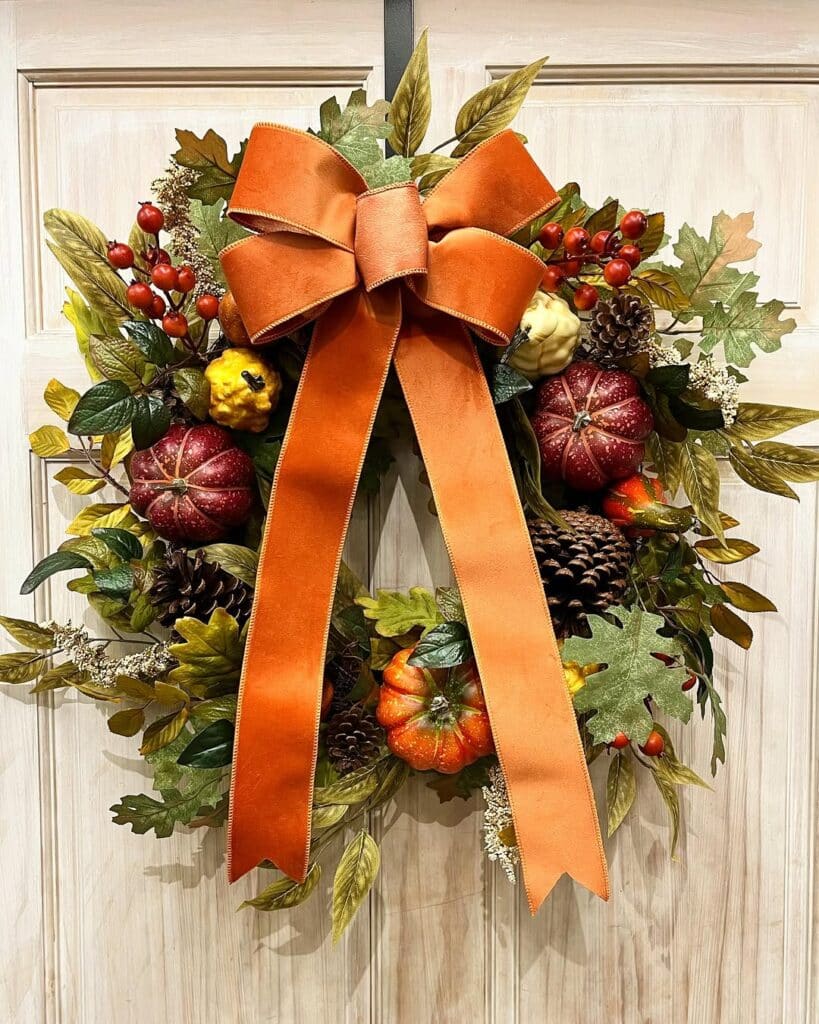 Wreath featuring a gourd cluster, autumn foliage, pinecones, and a velvet bow