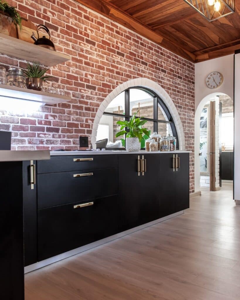 Modern cabinets in black with aged brick archways in a rustic style